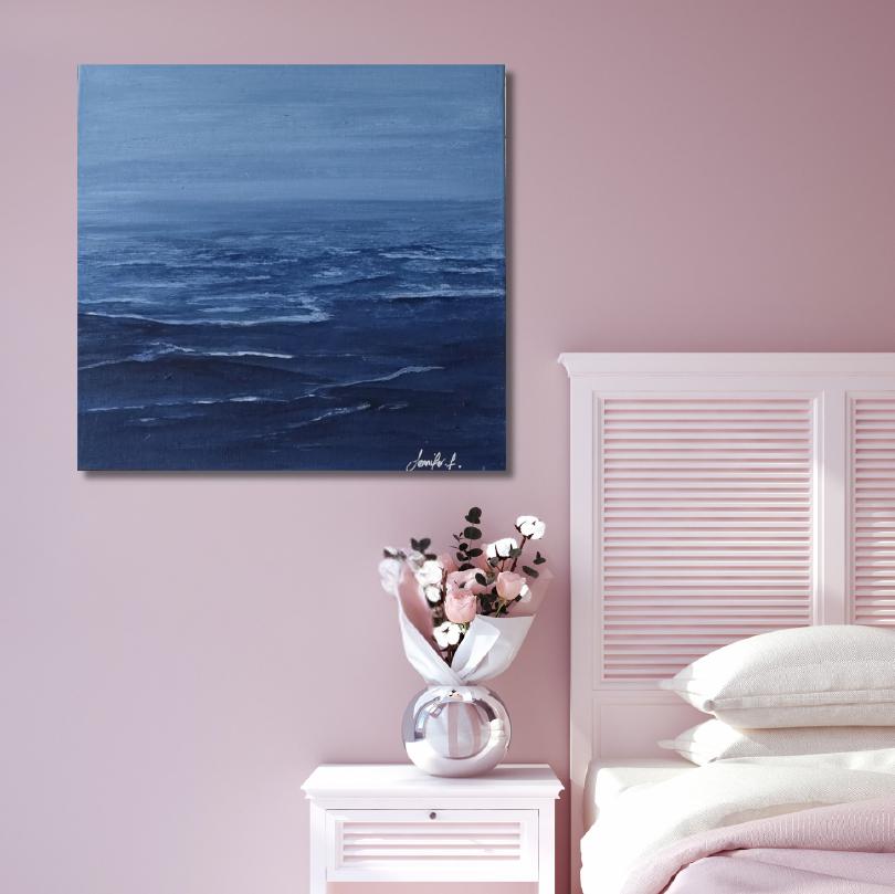Blue ocean painting on a pink wall above a nightstand with flowers and a bed.